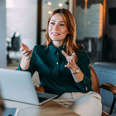 lady sat at desk with laptop mid conversation